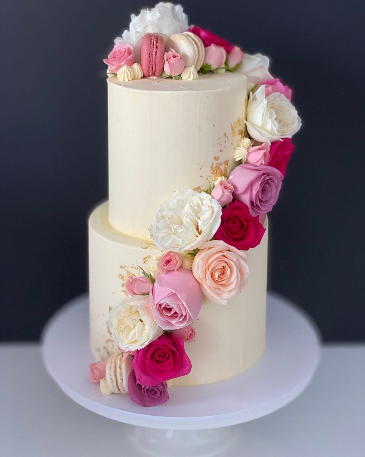 Two-tier ivory cake with gold leaf and a cascade of pink, white and magenta roses by Eats & Sweets